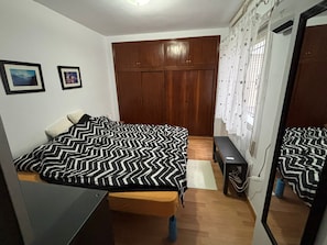 Ein Schlafzimmer mit Bett, Schreibtisch, Kleiderschrank und Spiegel.