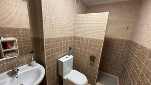 Casa de banho com lavatório, sanita e zona de duche.