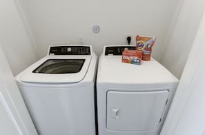 Una sala de lavandería con dos lavadoras y detergente Tide Bounce.