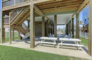 Una terraza de madera con mesas de picnic y una hamaca.