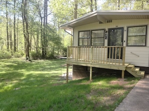 Een gelijkvloers vakantiehuis met een houten terras en een klein voortuintje.