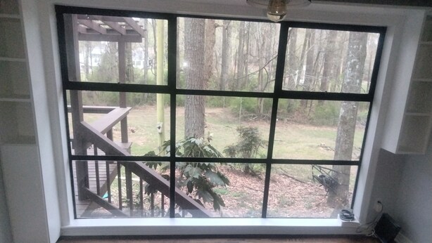 A room with a large window overlooking a deck and a wooded area. - Quiet 2-bedroom house in fantastic Fairburn with cool AC. (Fairburn)