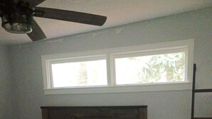 A bedroom with a bed, a ceiling fan, a window, and a wooden ladder. - Quiet 2-bedroom house in fantastic Fairburn with cool AC. (Fairburn)