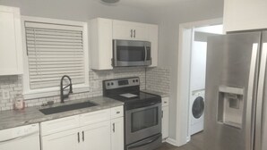 A modern kitchen with white cabinets, stainless steel appliances, a built-in oven, and a microwave. - Quiet 2-bedroom house in fantastic Fairburn with cool AC. (Fairburn)