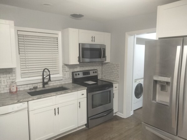 A modern kitchen with white cabinets, stainless steel appliances, a built-in oven, and a microwave.