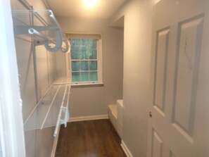 A narrow hallway with a window, a door, and a metal shelf unit.