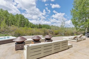 An outdoor relaxation area with a hot tub, lounge chairs, and a stone fireplace. - The Overlook Telluride- Includes 2 Ski Passes (Mountain Village)