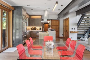 A modern kitchen with stainless steel appliances, a central island, and red chairs around a glass table. - The Overlook Telluride- Includes 2 Ski Passes (Mountain Village)