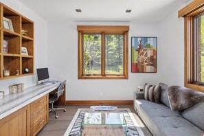A modern living room with a desk, computer, and a large window with a view of trees. - The Overlook Telluride- Includes 2 Ski Passes (Mountain Village)