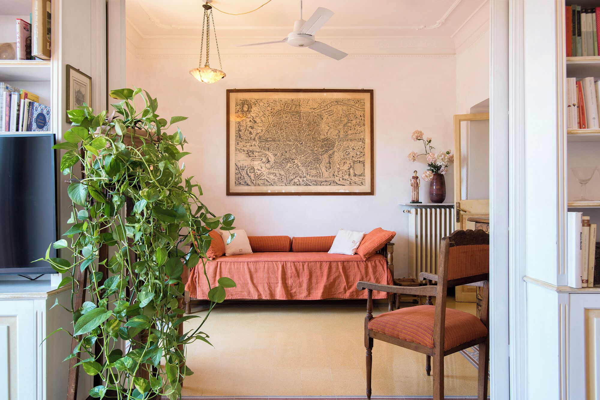 A cozy room with a bed, a chair, a bookshelf, and a large map on the wall.