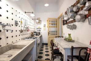 A compact kitchen with a gas stove, a sink, and a dining area with a table and chairs. - Colosseo The Family Home in Monti (Roma)