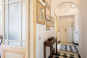 A hallway with a checkered floor, a wooden bench, and framed pictures on the wall. - Colosseo The Family Home in Monti (Roma)