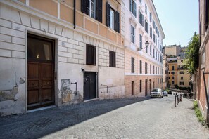 Una estrecha calle adoquinada bordeada por edificios históricos con grandes puertas y contraventanas de madera.