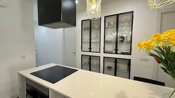A modern kitchen with a central island, black cabinets, and a decorative light fixture.