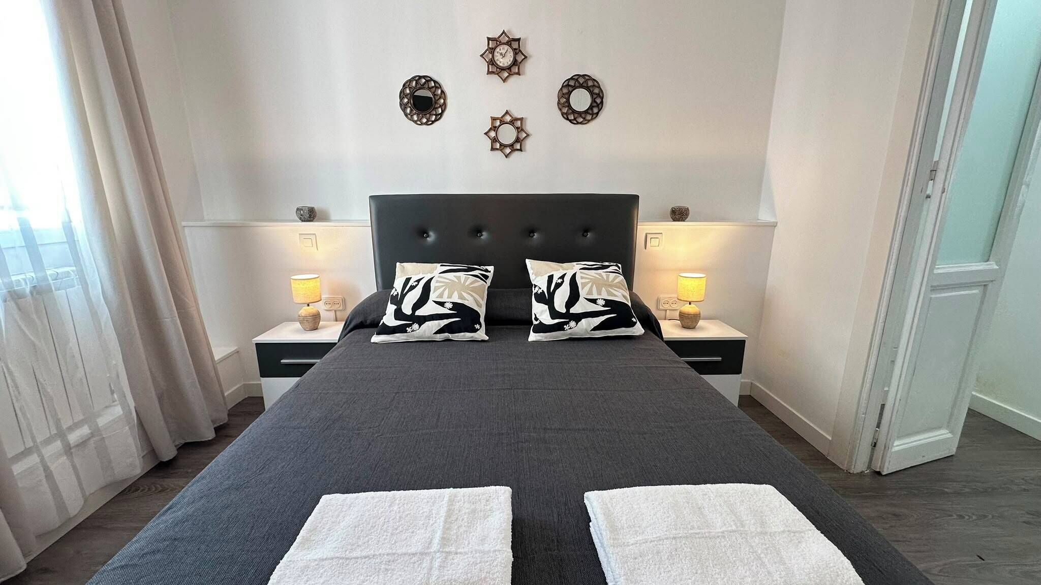 Ett hotellrum med en stor säng, två sängbord med lampor och dekorativa väggspeglar.