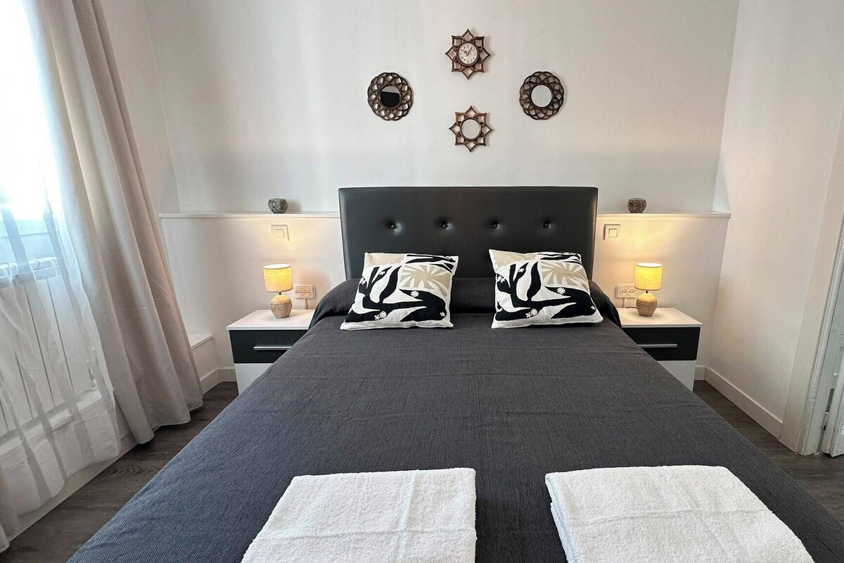Ett hotellrum med en stor säng, två sängbord med lampor och dekorativa väggspeglar.