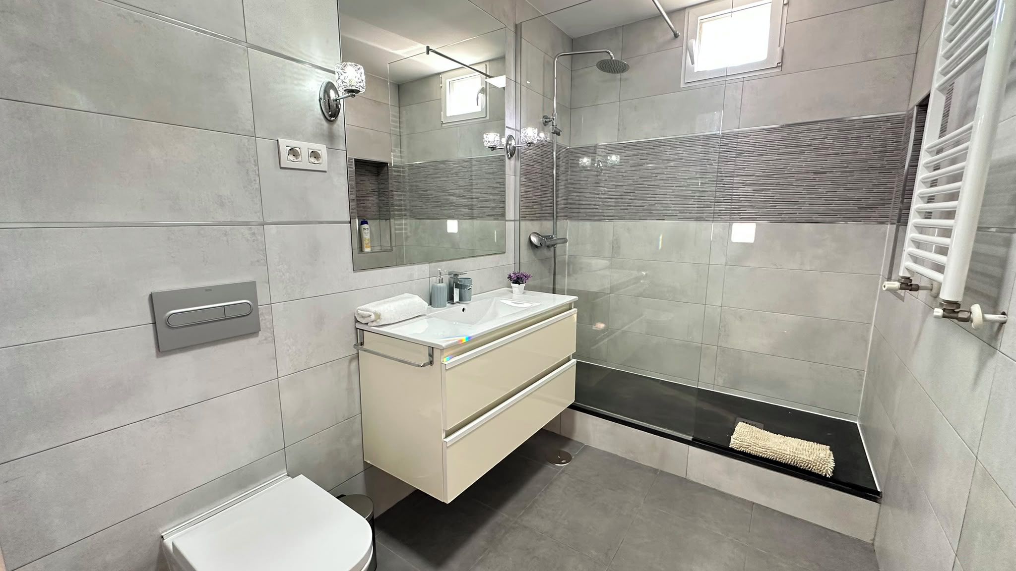 Une salle de bain moderne avec une douche à parois de verre, un lavabo blanc et des toilettes.