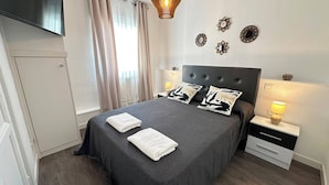 A neatly made bed with two white towels, a dark headboard, and bedside lamps. - Rooms Cabeza (Madrid)