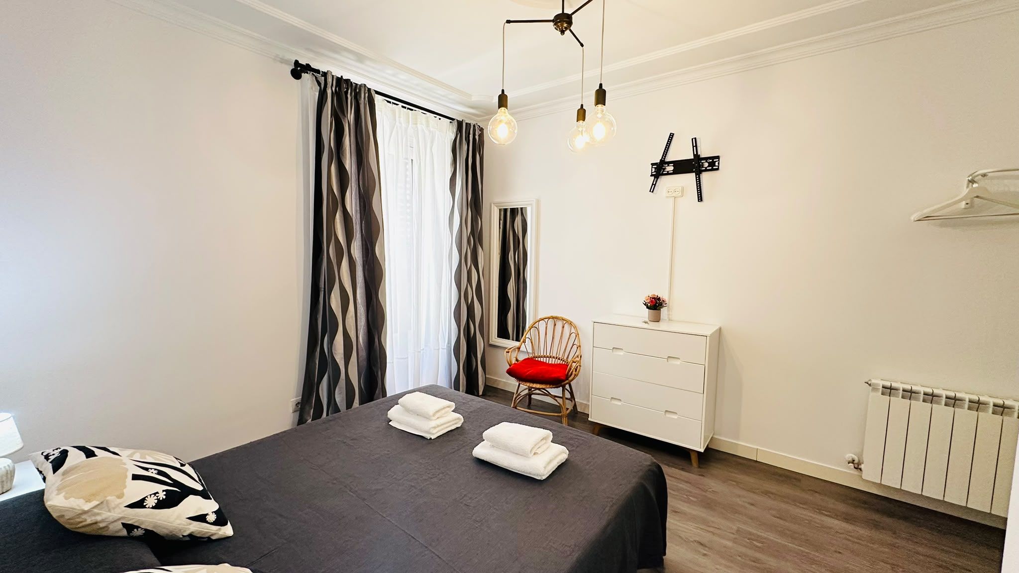 Un dormitorio con cama, cómoda, silla y radiador.
