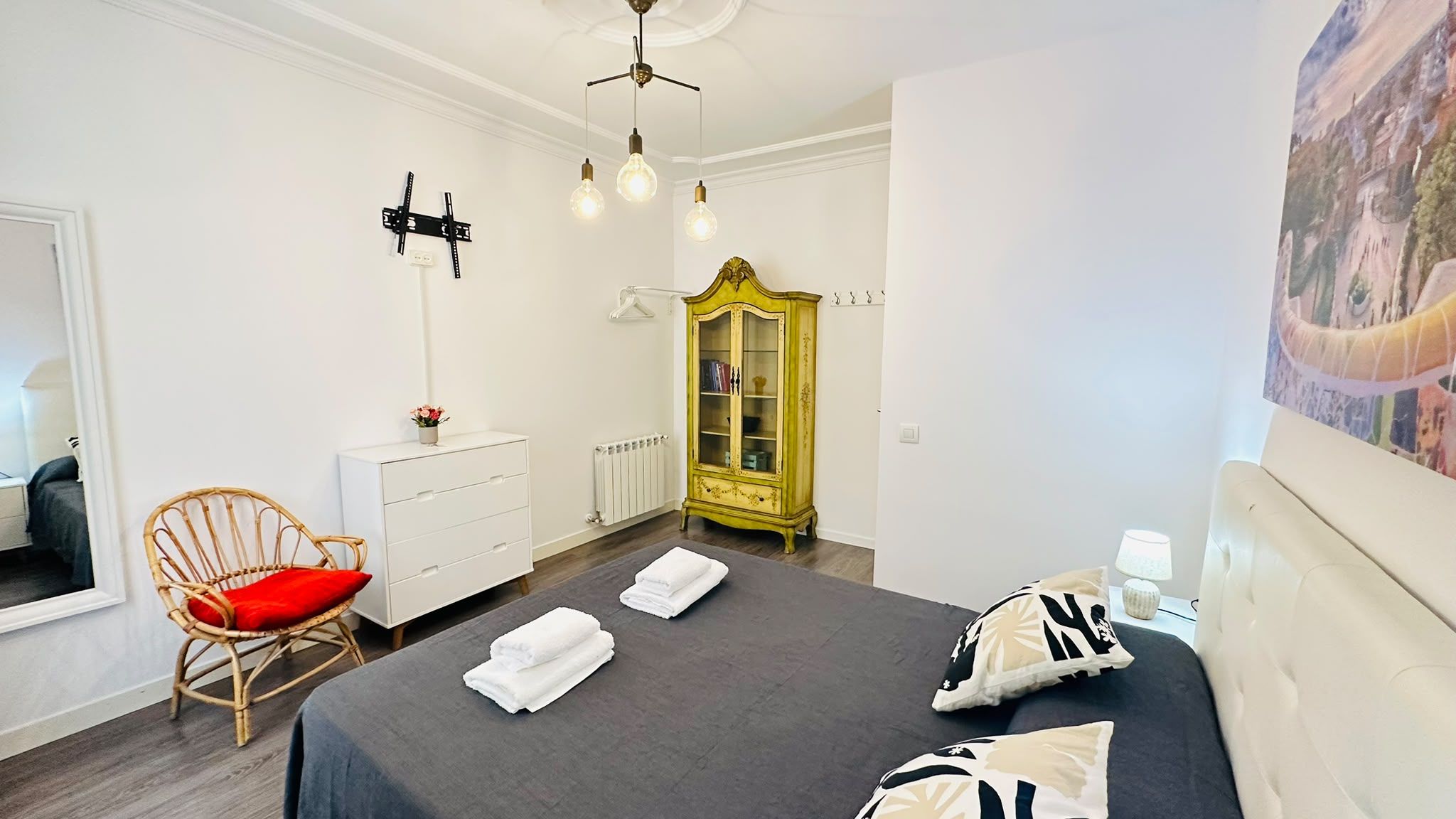 Een slaapkamer met een bed, een dressoir, een stoel, een kast en een schilderij aan de muur.