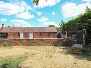A brick building with a white door, a small window, and a brick wall. - The Lodge (Shrewsbury)