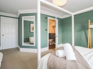 A room with a bed, a door, a mirror, and a bathroom visible through an open door. - The Lodge (Shrewsbury)