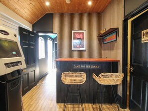 A bar area with a neon sign, two wicker chairs, and a sign that reads 'CAME FOR THE DRAMA'. - The Lodge (Shrewsbury)