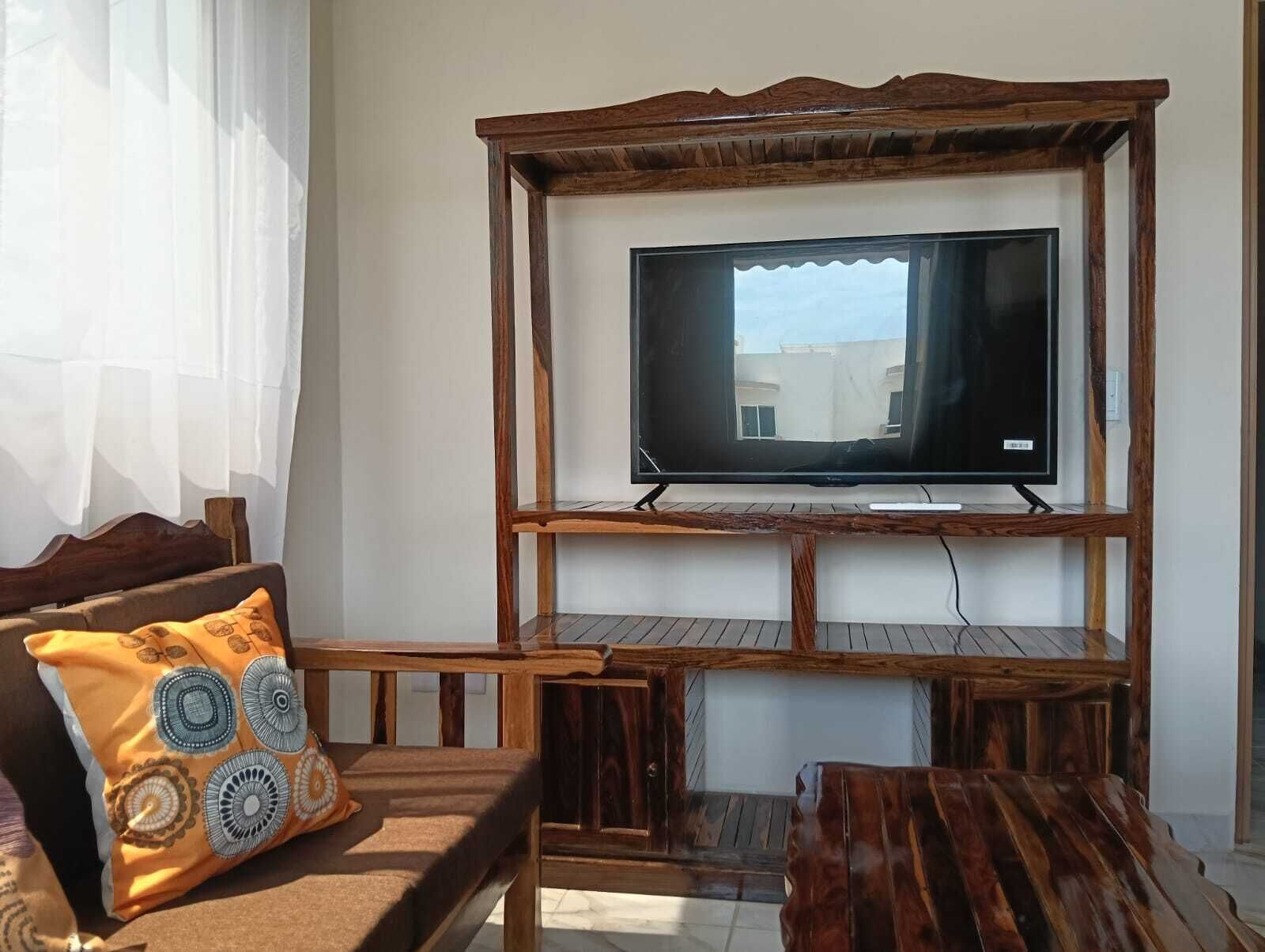 Una sala de estar con un mueble de madera para entretenimiento, un sofá y una mesa de centro.