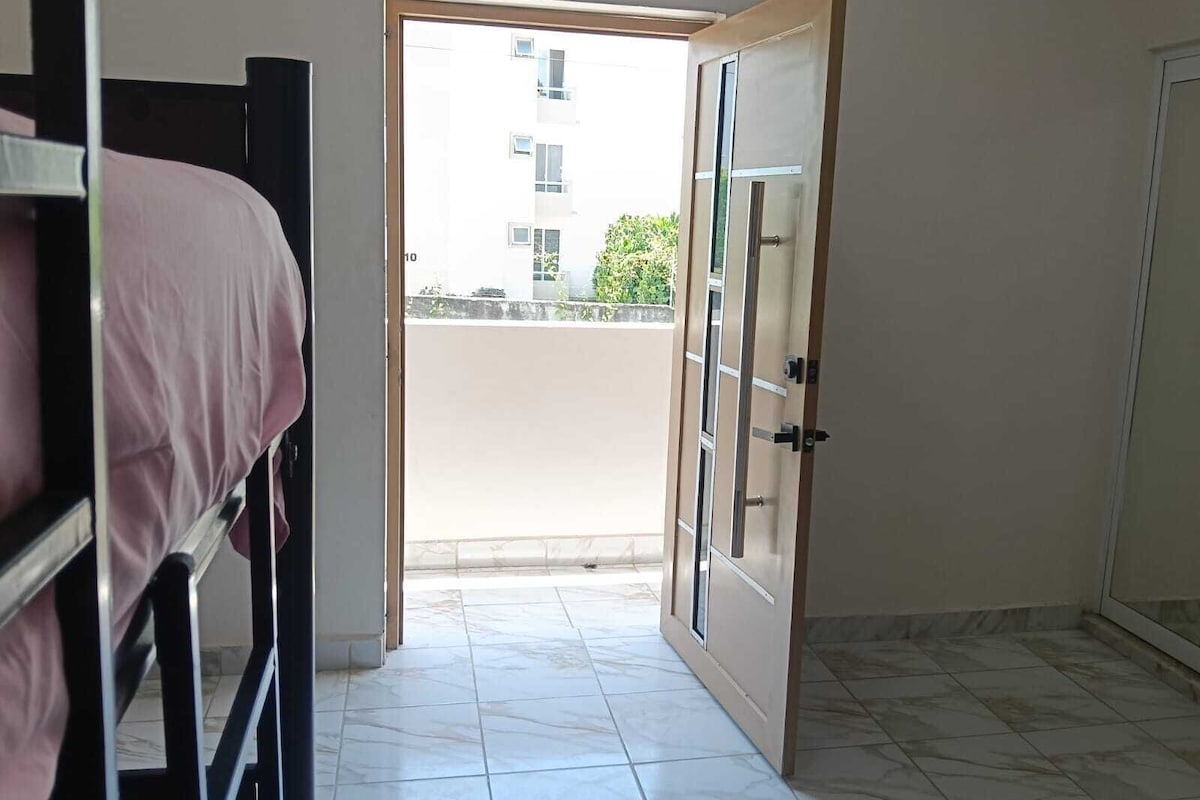 A room with a bunk bed, a door leading to an outdoor balcony, and a tiled floor.