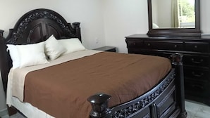 Un dormitorio con una cama grande, un aparador y un espejo.