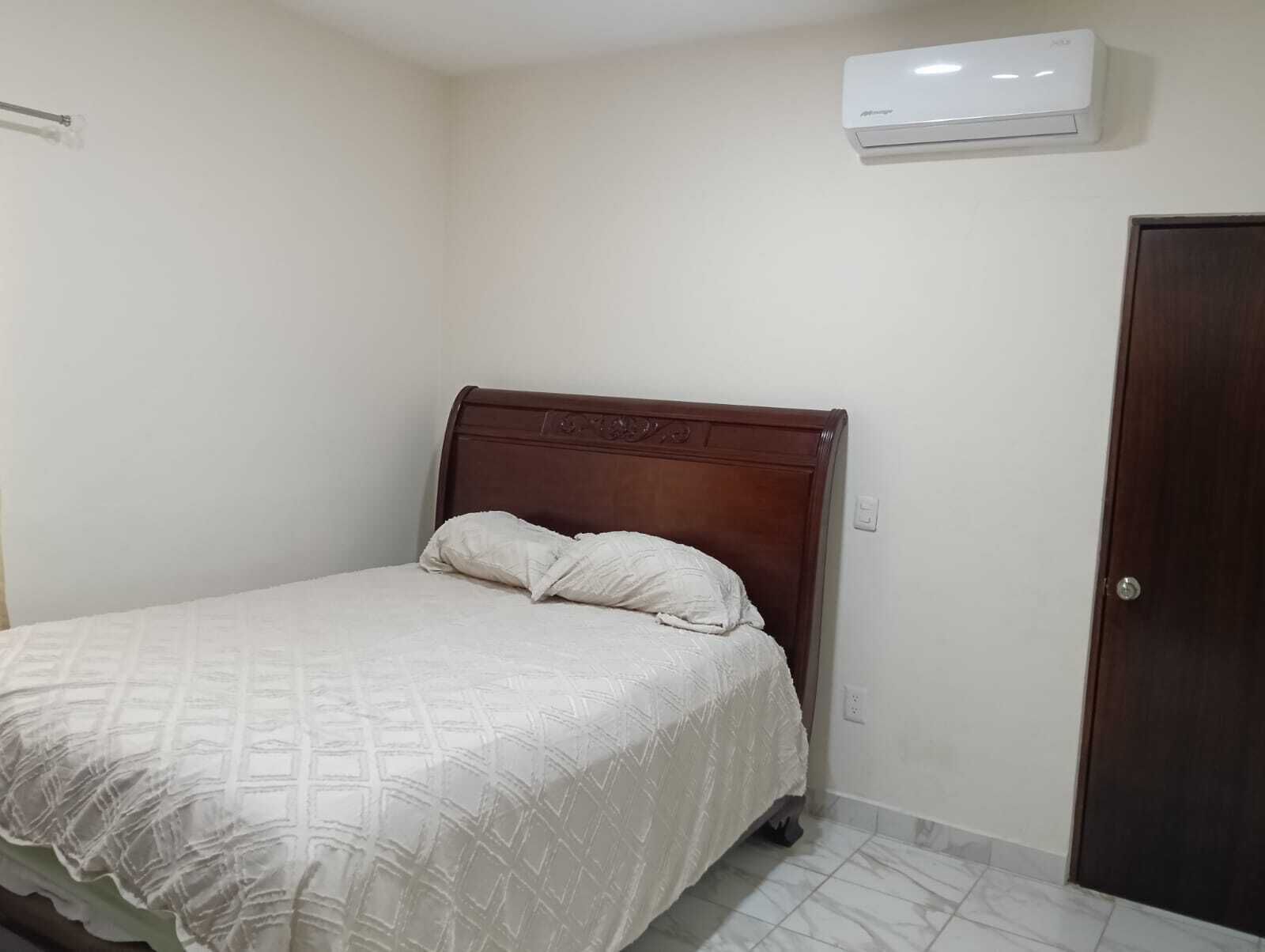 Une chambre à coucher avec un lit, une porte et un appareil de climatisation.