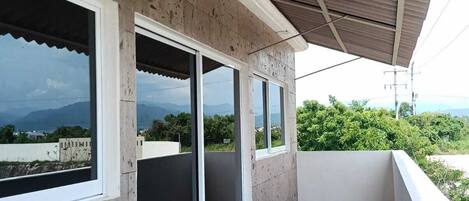 En balkon med udsigt over landskabet, et overdækket område med et metal tag og et flisegulv.