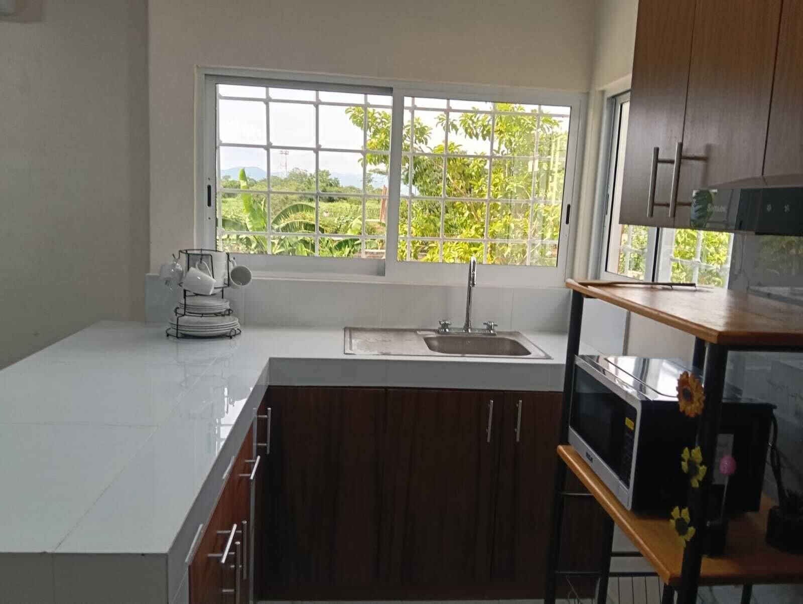 Una cocina con ventana, un lavamanos y armarios.