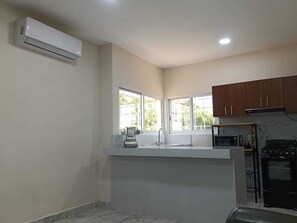 A kitchen with a built-in stove, a microwave, and a sink. There are windows providing natural light and a view of the outside.