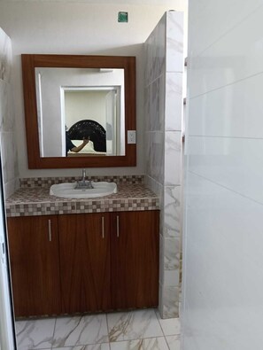 A bathroom with a wooden vanity, a mirror, and a sink. - Casa Sauz by Otium (Mezcales)