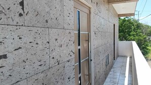 Fachada de edificio con tejas, una puerta y un balcón con barandilla.