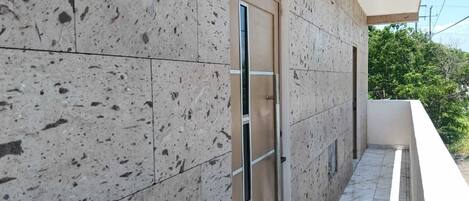 Fachada de edificio con tejas, una puerta y un balcón con barandilla.