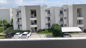 Un immeuble résidentiel à plusieurs étages, doté de balcons, d’un espace de stationnement et surplombant un ciel dégagé.