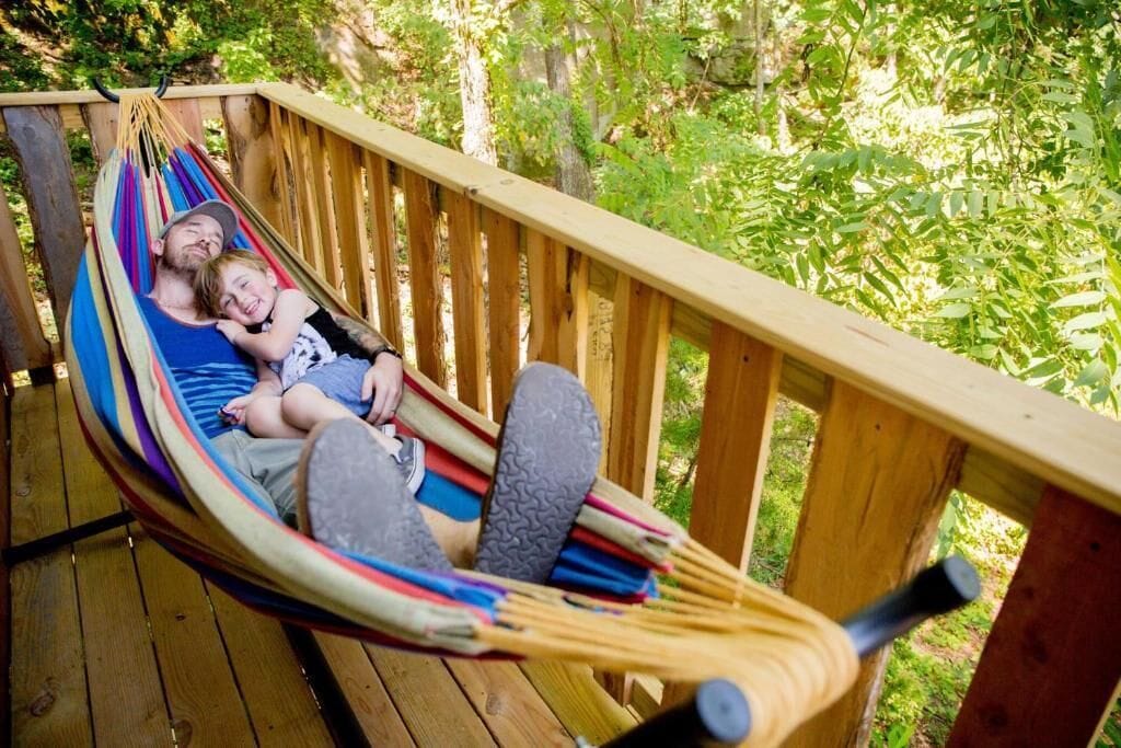 A hammock on a wooden deck with a natural backdrop.