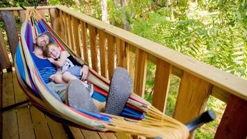 A hammock on a wooden deck with a natural backdrop.