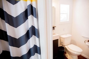 Un baño con inodoro blanco, lavamanos y ventana.