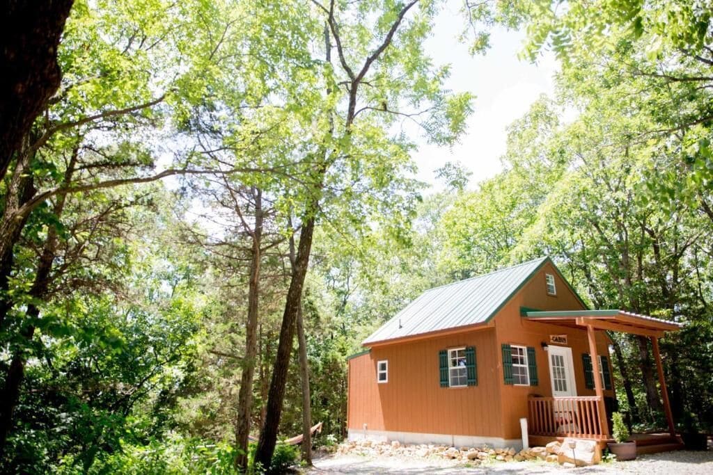 Eine kleine Holzhütte mit Veranda, umgeben von Bäumen.