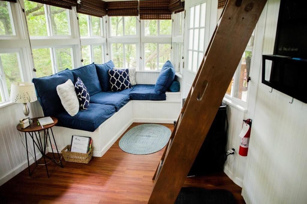 A cozy room with a blue sectional sofa, a small side table, a wicker basket, and a round rug.