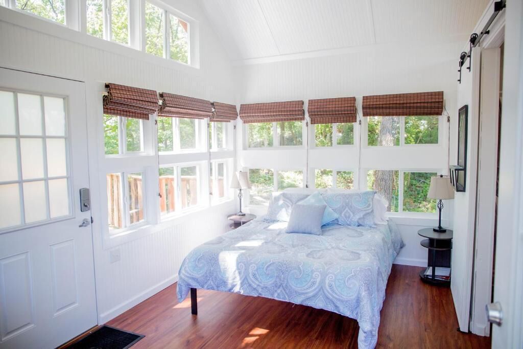 Ein Schlafzimmer mit einem großen Bett, mehreren Fenstern und einer Tür.