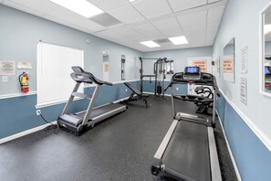Ein Fitnessraum mit Laufbändern, einer Bank und Gewichtsmaschinen.