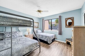 A room with bunk beds, a desk, a chair, a dresser, a window with curtains, and a ceiling fan. - New Listing! Master Balcony* 3 Pools* Walk to Sand (Panama City Beach)