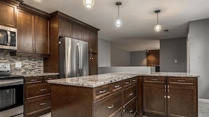 Una cocina moderna con armarios de madera oscura, electrodomésticos de acero inoxidable y encimera de granito.