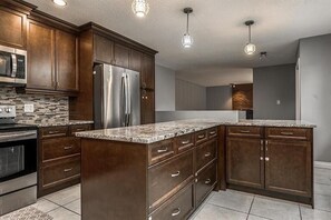 A modern kitchen with dark wood cabinets, stainless steel appliances, and a granite countertop. - Private Room - Opposite Hospital and Uni (Calgary)