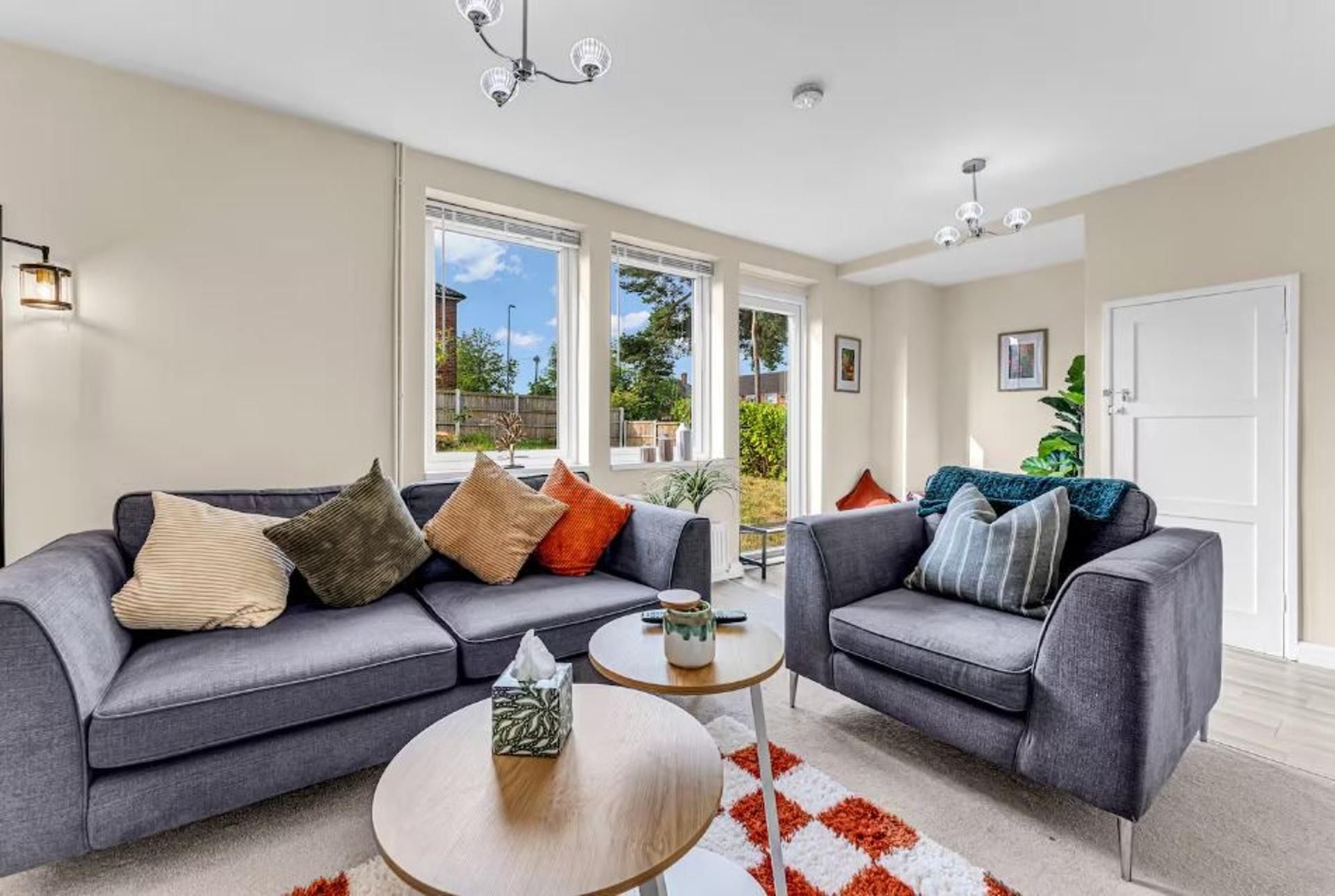 A modern living room with two grey sofas, a round coffee table, and a view of the outdoors through large windows.