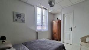 Una camera da letto con un letto, un armadio, una finestra con tende e una lampada a sospensione.